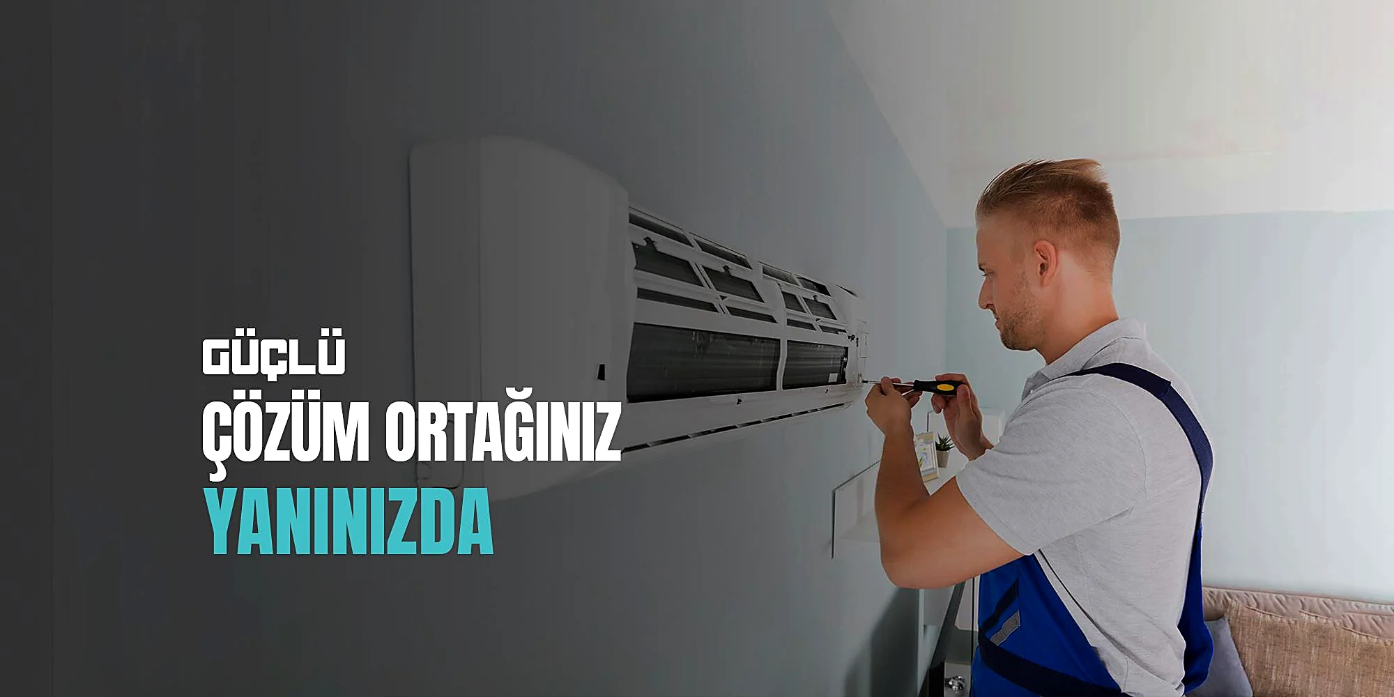 Teknisyen duvar tipi klimanın ön panelini tornavidayla açıyor